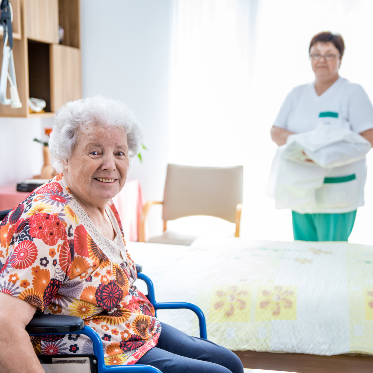 Bild mit einer Bewohnerin im Rollstuhl und einer Pflegekraft